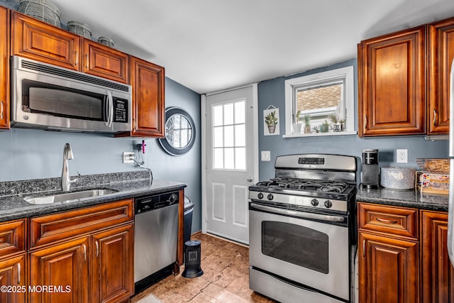 kitchen with sink, dark stone countertops, a wealth of natural light, and stainless steel appliances