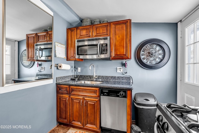 kitchen with sink, stainless steel appliances, and dark stone countertops