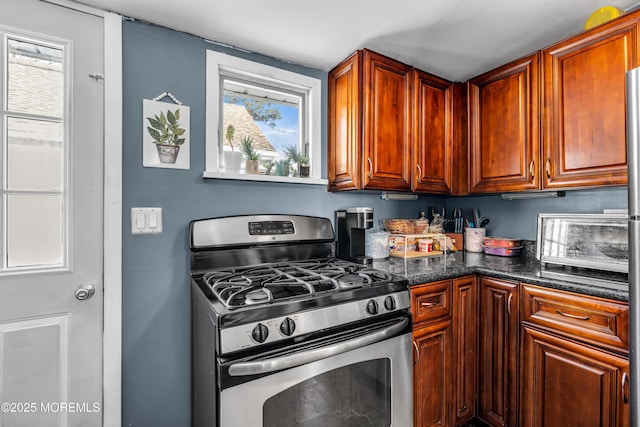 kitchen with stainless steel gas stove and dark stone counters