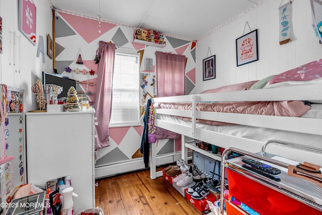 bedroom with hardwood / wood-style floors and a baseboard heating unit