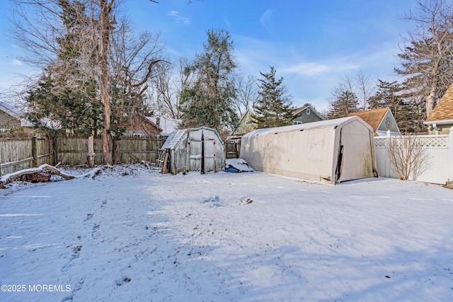 snowy yard featuring a storage unit