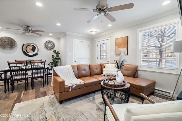 living room with ceiling fan, a baseboard radiator, ornamental molding, and wood-type flooring