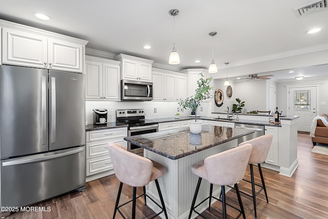 kitchen with stainless steel appliances, a center island, white cabinets, and a kitchen bar