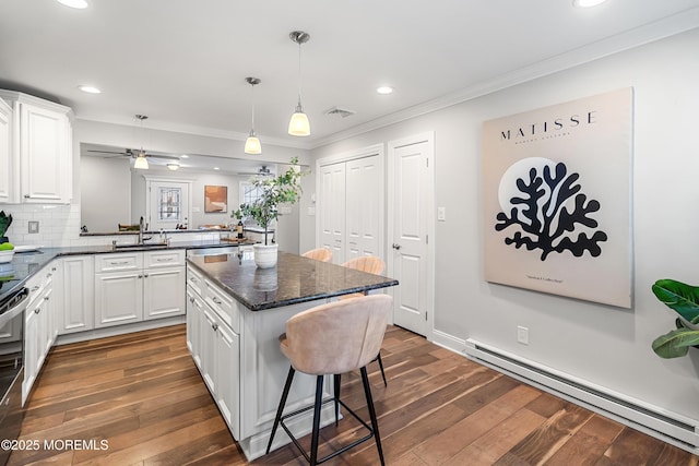 kitchen featuring a kitchen island, white cabinetry, backsplash, baseboard heating, and kitchen peninsula