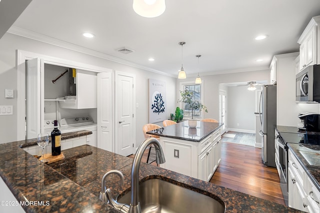 kitchen featuring stainless steel appliances, a center island, pendant lighting, and white cabinets