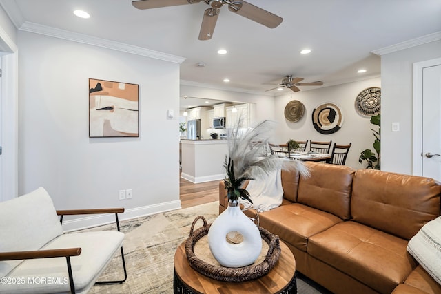 living room with crown molding, ceiling fan, and light wood-type flooring