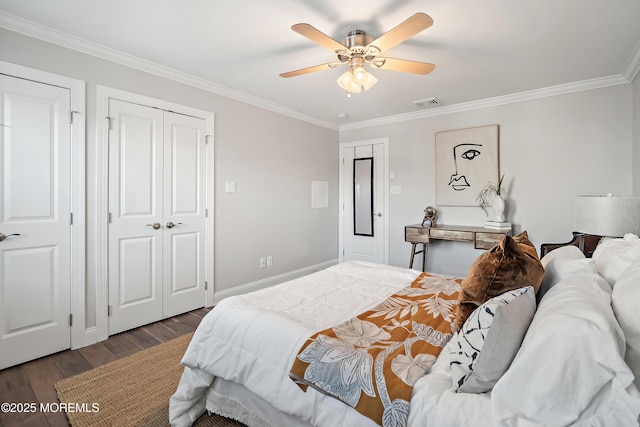 bedroom featuring multiple closets, ornamental molding, wood-type flooring, and ceiling fan