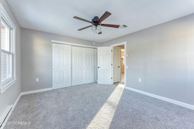 unfurnished bedroom featuring ceiling fan, light colored carpet, baseboard heating, and a closet