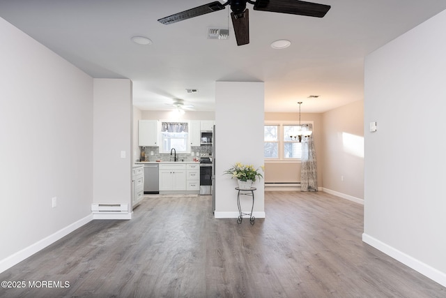 unfurnished living room featuring ceiling fan with notable chandelier, sink, hardwood / wood-style floors, and a baseboard heating unit