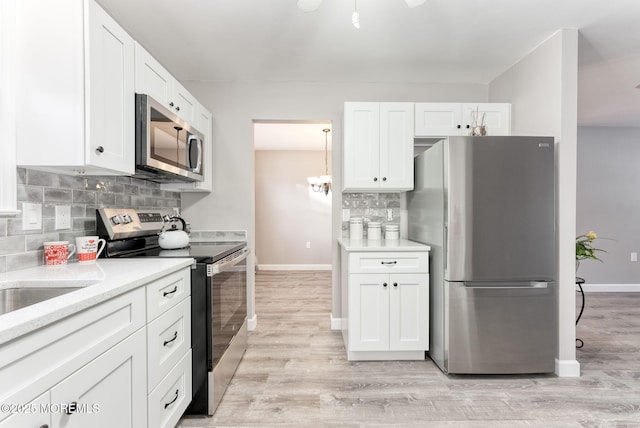 kitchen featuring white cabinetry, appliances with stainless steel finishes, light wood-type flooring, and backsplash