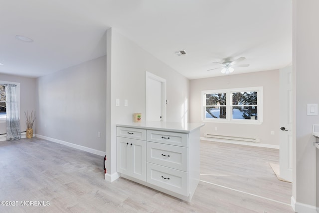 kitchen with ceiling fan, white cabinets, baseboard heating, and light hardwood / wood-style floors