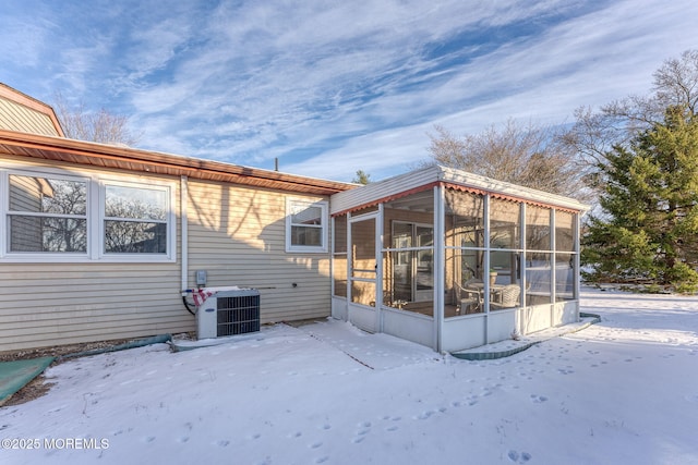 snow covered house with a sunroom and central AC