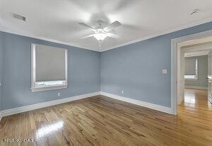 empty room with baseboards, wood finished floors, and crown molding