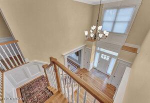 foyer with a chandelier, ornamental molding, stairway, and wood finished floors