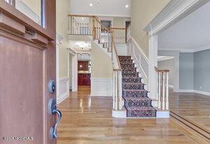 foyer entrance with a decorative wall, stairway, wood finished floors, and crown molding