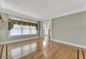 spare room featuring crown molding, baseboards, and wood finished floors