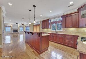 kitchen with reddish brown cabinets, a kitchen breakfast bar, open floor plan, decorative light fixtures, and light wood-style floors