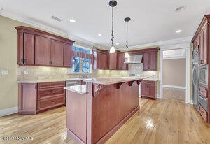 kitchen featuring wall chimney exhaust hood, a kitchen bar, light countertops, and a center island