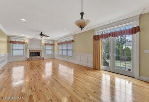 unfurnished living room featuring a fireplace with raised hearth, plenty of natural light, wood finished floors, and crown molding