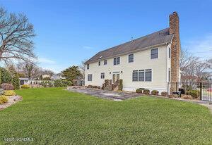 back of property with a lawn, a chimney, and fence