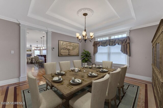 dining room featuring baseboards, a chandelier, a raised ceiling, and wood finished floors