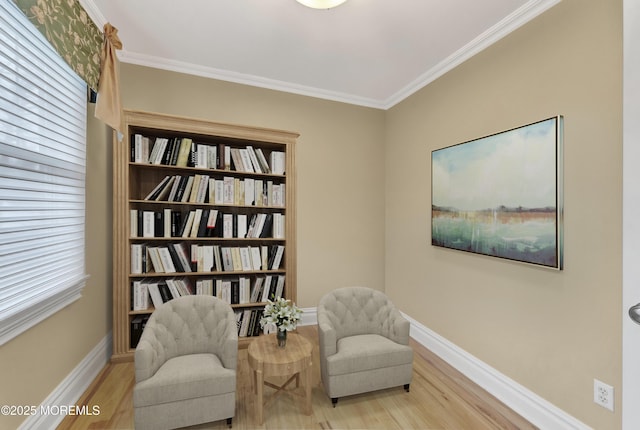 living area with baseboards, ornamental molding, and light wood-style floors