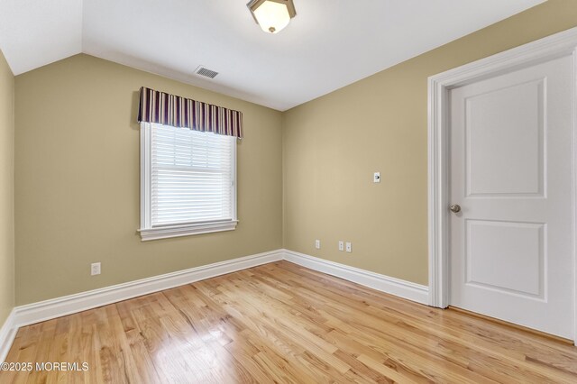 unfurnished room with lofted ceiling, wood finished floors, visible vents, and baseboards