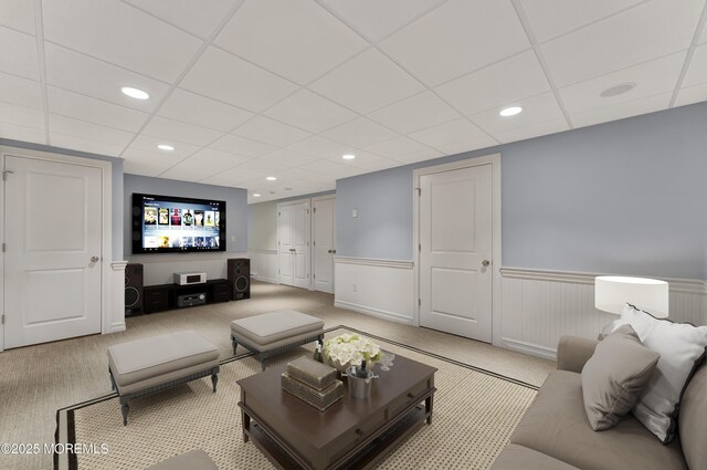 living area with a wainscoted wall, recessed lighting, a paneled ceiling, and light colored carpet