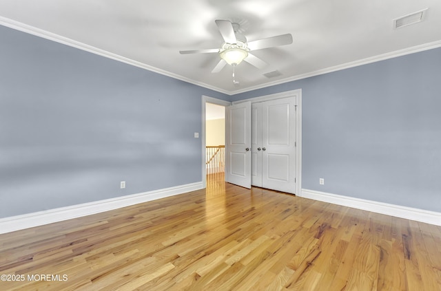 unfurnished bedroom featuring baseboards, visible vents, crown molding, light wood-style floors, and a closet