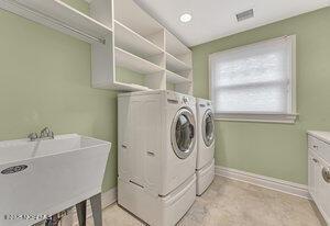 laundry room featuring laundry area, visible vents, baseboards, washer and clothes dryer, and a sink