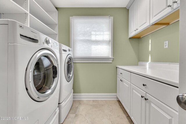 laundry room featuring washing machine and dryer, cabinet space, and baseboards