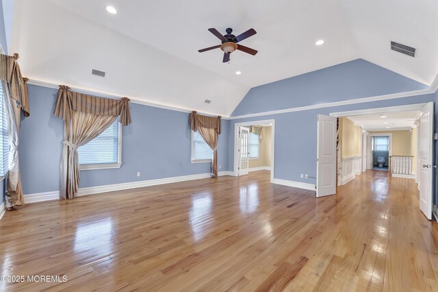 unfurnished living room featuring light wood-style floors, visible vents, vaulted ceiling, and crown molding