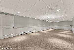 carpeted empty room featuring baseboard heating, recessed lighting, a paneled ceiling, and a notable chandelier