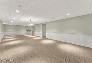 basement with carpet, wainscoting, and a drop ceiling