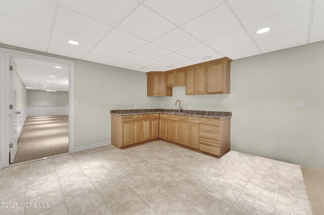 kitchen with dark countertops, recessed lighting, a sink, a drop ceiling, and baseboards