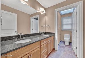 bathroom with tile patterned floors, a sink, toilet, and double vanity