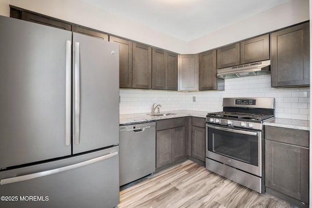 kitchen featuring stainless steel appliances, light hardwood / wood-style floors, tasteful backsplash, and light stone countertops