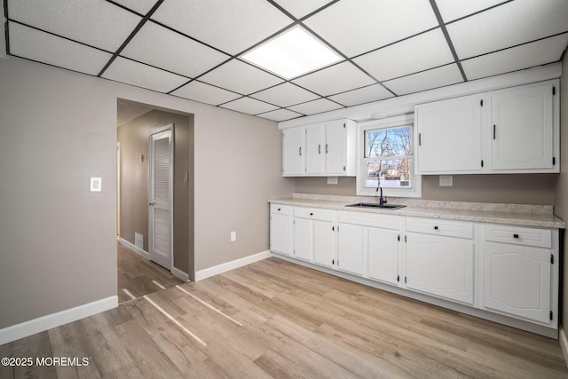 kitchen with white cabinets, sink, and light hardwood / wood-style flooring