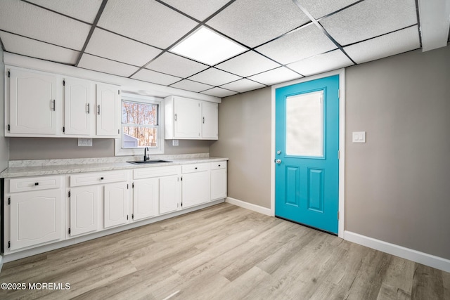 kitchen featuring a paneled ceiling, white cabinetry, light hardwood / wood-style flooring, and sink