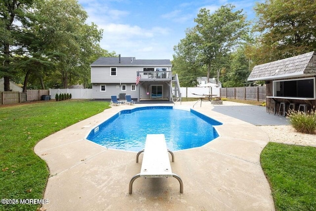 view of swimming pool featuring a diving board, a patio, a yard, and exterior bar