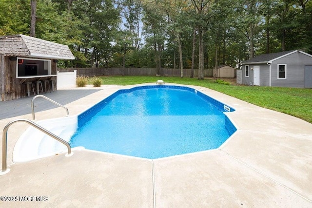 view of pool with a yard, a patio area, a storage shed, and an outdoor bar