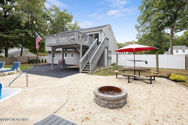 back of property with a wooden deck, a patio area, and a fire pit