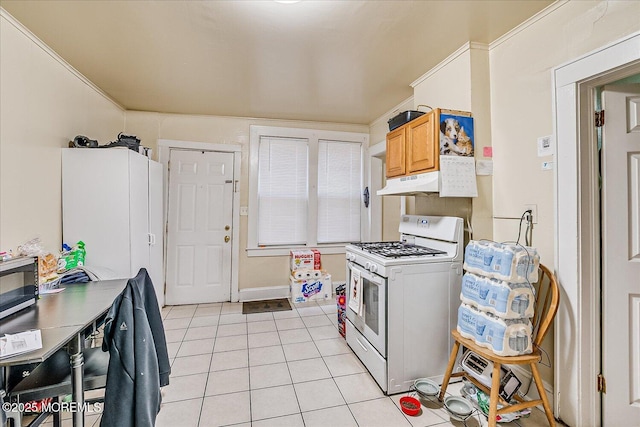 kitchen featuring light brown cabinetry, light tile patterned flooring, crown molding, and white gas range oven