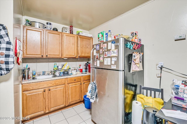 kitchen with tasteful backsplash, light tile patterned floors, sink, and stainless steel refrigerator