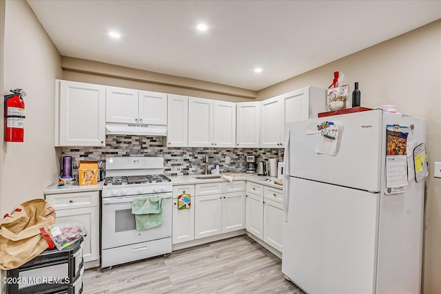 kitchen with white cabinetry, backsplash, white appliances, and light hardwood / wood-style flooring