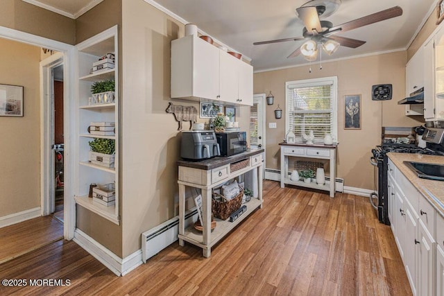 kitchen with baseboard heating, stainless steel gas range, white cabinetry, light wood-type flooring, and crown molding