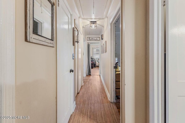 corridor with ornamental molding and light wood-type flooring