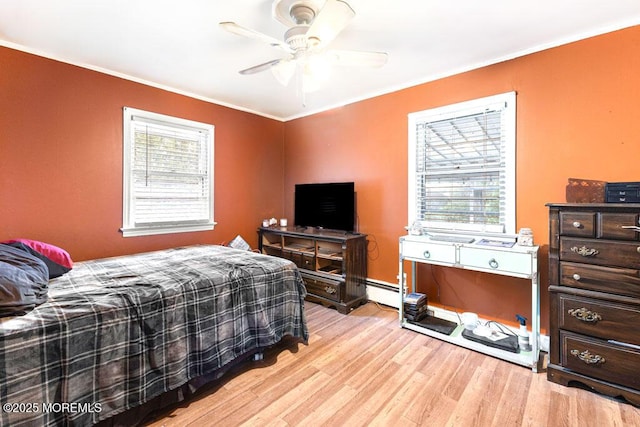 bedroom with ceiling fan, a baseboard radiator, multiple windows, and light hardwood / wood-style flooring