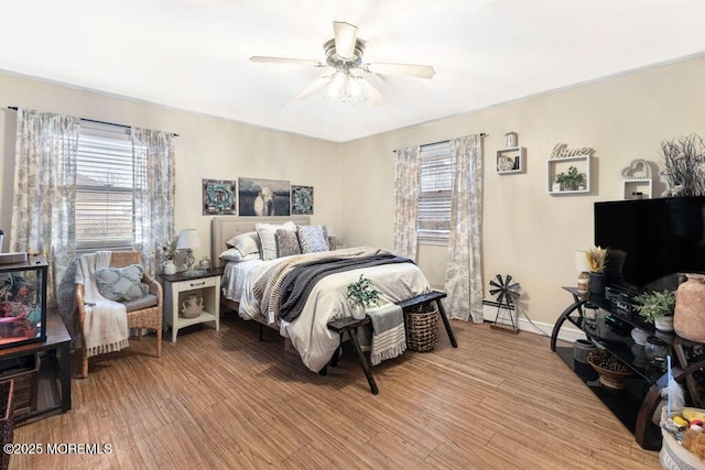 bedroom featuring ceiling fan, light wood-type flooring, and multiple windows