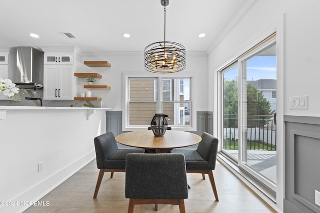 dining space featuring an inviting chandelier, ornamental molding, and light hardwood / wood-style floors